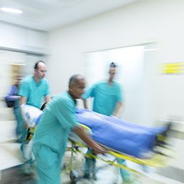 Doctors wheeling patient in emergency room